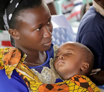 A mother holding a sleeping child during a service