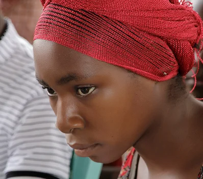 A young woman in a red headscarf looking down in reflection